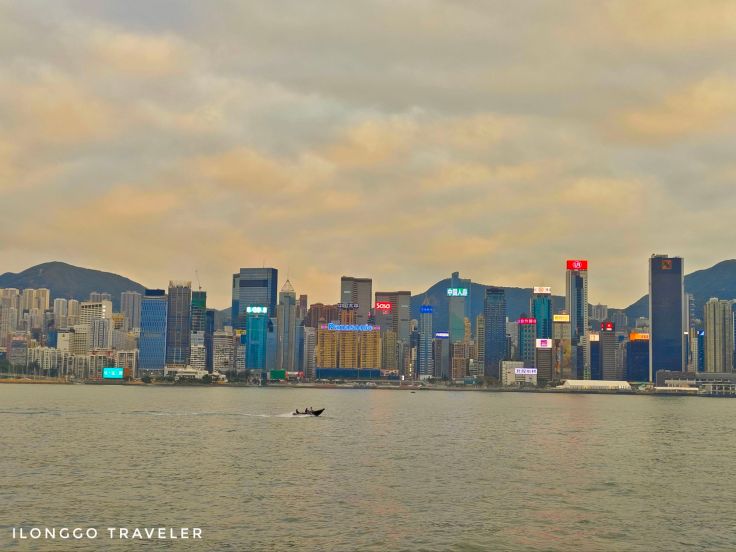 Panoramic view of Victoria Harbour with ferries and Hong Kong Island skyline at dusk