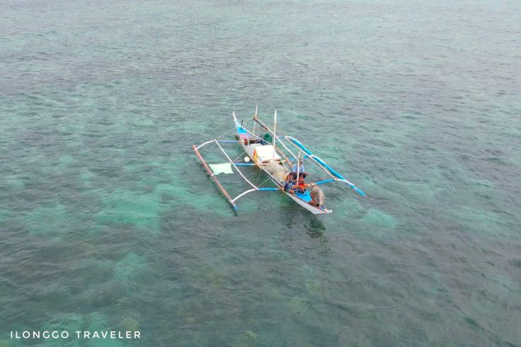 Single fishing boat casting nets on the blue sea off Concepcion, Iloilo, Philippines